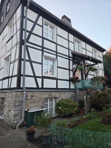 Sanierte Fachwerkfassade über Natursteinsockel in Hemer während der Wartungskontrolle.